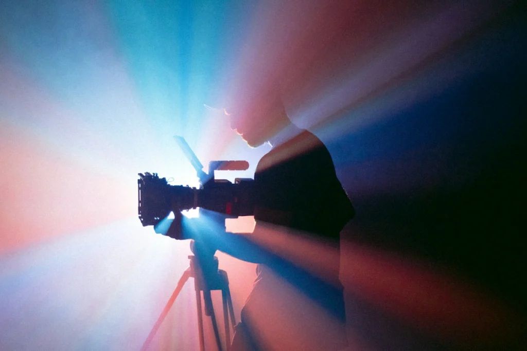 Camarógrafo Grabando Con Una Cámara Sobre Un Tripié Bajo Luces Azules Y Rojas
