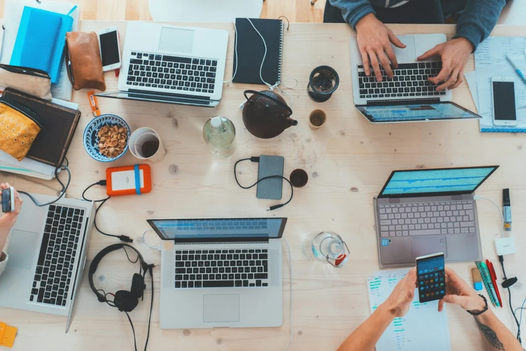 Equipo De Trabajo Reunido Alrededor De Una Mesa Con Laptops Planeando Una Estrategia De Marketing Digital