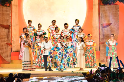 Fotografía De Plano General En Un Escenario De La Feria Tabasco. El Gobernador Del Estado Le Coloca Oficialmente La Banda Bordada De 'Embajadora' A Una Joven Que Representa Al Municipio De Centla, Quien Modela Sosteniendo La Amplia Falda Bordada En Flores De Su Traje Regional.