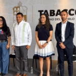 Aquí tienes el texto alternativo (Alt Text) optimizado para accesibilidad web y motores de búsqueda (SEO), diseñado para que los lectores de pantalla y los algoritmos de indexación de noticias comprendan el contexto visual de la imagen: Texto Alternativo (Alt Text) Fotografía oficial de la conferencia matutina del Gobierno de Tabasco. En el centro, el Gobernador Javier May Rodríguez viste una guayabera blanca con bordados verdes; a su derecha, la Secretaria de Turismo y Desarrollo Económico, Katia Ornelas Gil, porta una playera oficial negra de la Feria Tabasco 2026.