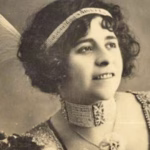 Retrato De Estudio En Sepia De Esperanza Iris, La Cantante Y Empresaria Teatral Tabasqueña. La Artista Aparece Sonriendo Levemente Y Mirando Hacia Arriba Y A La Derecha. Luce Un Peinado Alto Con Rizos Y Una Banda Para La Cabeza Enjoyada Con Un Colgante. Un Gran Plumaje Blanco Asoma Por Detrás De Su Cabeza A La Izquierda. Lleva Un Collar Tipo Gargantilla Ancho Y Enjoyado Y Un Vestido Con Lentejuelas. El Fondo Es Un Degradado Suave Y Desenfocado.