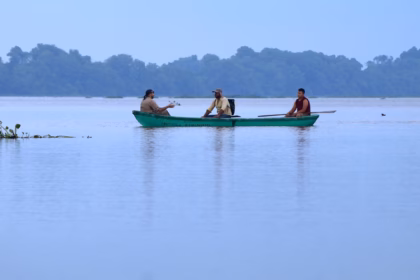aisaje panorámico de Potonchán en los Pantanos de Centla, Tabasco. Se observa una canoa verde con tres personas navegando sobre un espejo de agua sereno bajo un cielo nublado. Al fondo, una densa línea de manglares y selva completa el horizonte, transmitiendo una atmósfera de paz y conexión con la naturaleza.