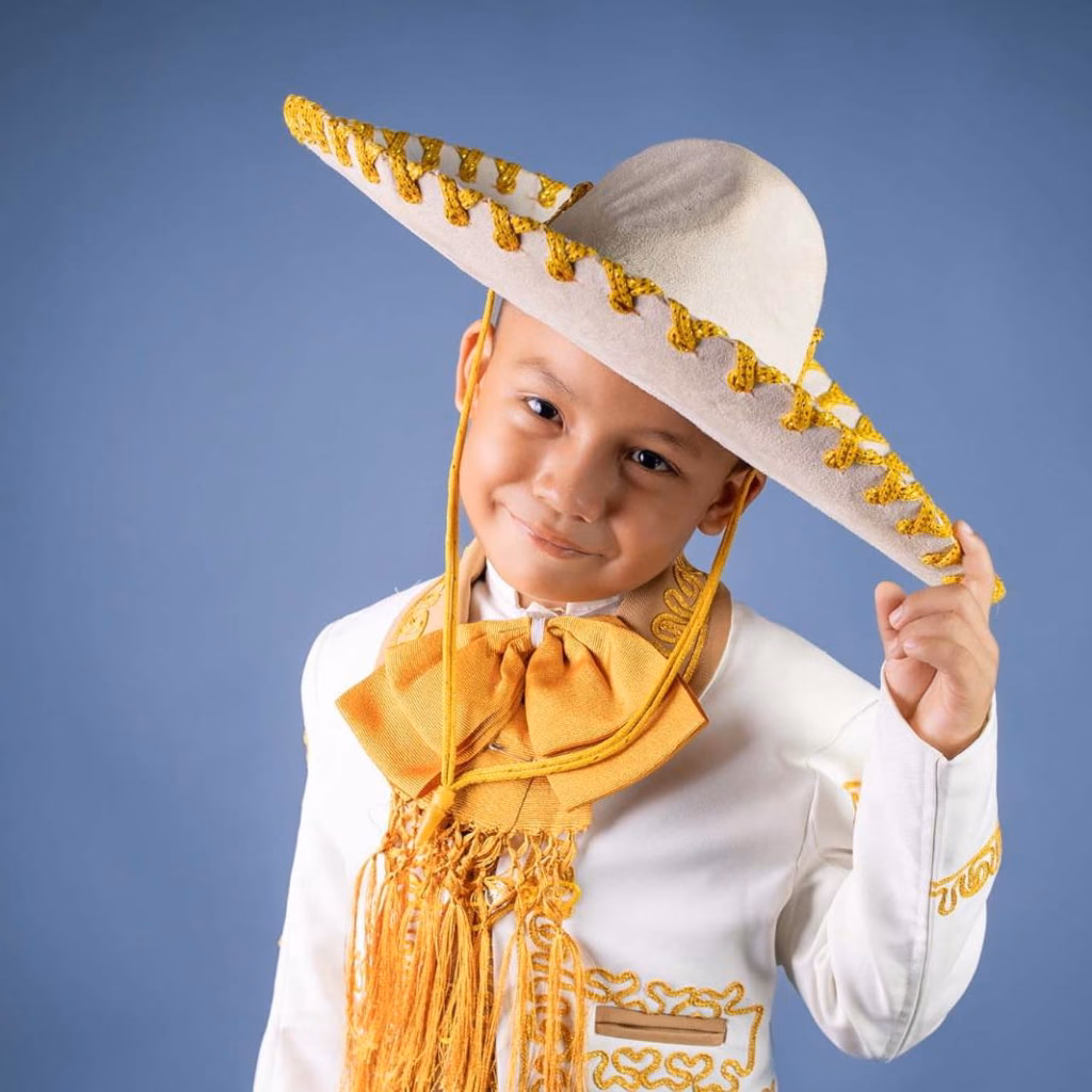 El Fenómeno De &Quot;El Charrito&Quot;: El Niño Que Teje Tradiciones Y Canta Con El Alma De Tabasco 71 Retrato De Estudio De Abraham &Quot;El Charrito&Quot; Sobre Un Fondo Azul Sólido. El Niño Luce Una Sonrisa Carismática Mientras Ajusta Su Sombrero De Charro Blanco Con Bordados Amarillos. Viste Un Traje De Gala Impecable Con Un Gran Moño Dorado.