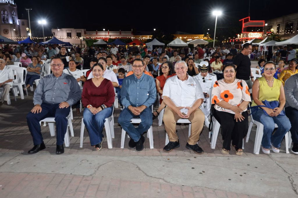 Fotografía En Plano Medio De Un Grupo De Autoridades Y Ciudadanos Sentados En La Primera Fila De Un Evento Nocturno Al Aire Libre. En El Centro Destacan El Alcalde De Centla, Saúl Armando Rodríguez, Y El Subsecretario De Cultura, Salvador Manrique Priego. 