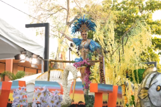 Mariú Mendoza Cabrera, Embajadora De Emiliano Zapata, Viste Un Traje De Gala Con Plumas Azul Turquesa Y Pedrería, Saludando Desde Un Carro Alegórico Decorado Con Flores De Lluvia De Oro Y Elementos Que Representan La Fauna Del Río Usumacinta.