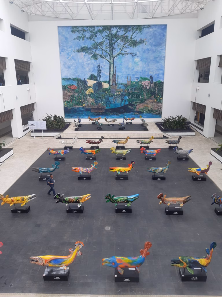 Pejelagarte: El Despertar De Los Gigantes De Fibra De Vidrio En El Corazón De Villahermosa 3 Una Fotografía Panorámica Del Patio Central De La Plaza “La Ceiba” En El Palacio Municipal Del Centro, Villahermosa. En Primer Plano, Sobre Un Espejo De Agua Reflectante Que Cubre El Suelo, Se Observan Decenas De Esculturas Monumentales De Pejelagartos De Fibra De Vidrio.