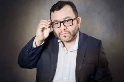 Retrato En Primer Plano Del Actor Mexicano Silverio Palacios. Aparece Con Una Expresión Seria Y Analítica, Ajustándose Sus Lentes De Armazón Negro.