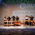 Fotografía De Un Ensamble De Marimbistas Participando En La Gran Final De Expresiones Culturales 2026 Sobre El Escenario Del Teatro Esperanza Iris. En La Imagen Se Observan Dos Marimbas De Madera; A La Izquierda, Cuatro Músicos (Tres Hombres Y Una Mujer) Ejecutan Una Pieza, Mientras Que A La Derecha, Una Pareja (Hombre Y Mujer) Toca El Segundo Instrumento.