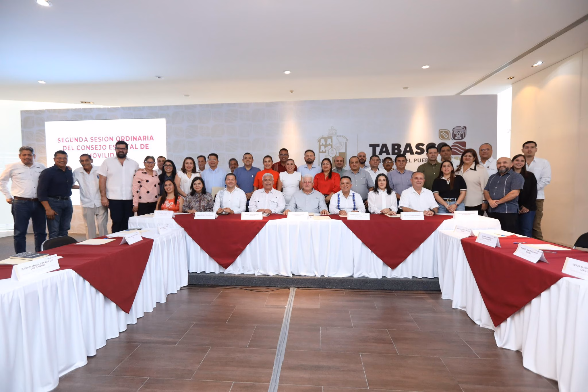 Tabasco Elimina El Taxímetro Y Crea Consejos Municipales De Movilidad 70 Fotografía Grupal A Color Tomada En Un Salón De Conferencias Moderno En Villahermosa, Tabasco. Muestra A Decenas De Personas, Incluidos Funcionarios Estatales, Alcaldes Y Líderes Del Sector Transporte, Posando De Pie Y Sentados Alrededor De Una Gran Mesa De Reuniones En Forma De U Cubierta Con Manteles Blancos Y Guindas. En El Centro, Sentados, Destacan El Secretario De Gobierno, José Ramiro López Obrador, Y El Secretario De Movilidad, Rafael Elías Sánchez Cabrales. Al Fondo, A La Derecha, Una Gran Pared Blanca Muestra El Logotipo Oficial Del Gobierno De Tabasco Con La Frase &Amp;Quot;Tabasco, Gobierno Del Pueblo&Amp;Quot;. A La Izquierda, Una Pantalla De Proyección Apagada Muestra Un Cartel Rosa Con El Texto &Amp;Quot;Segunda Sesión Ordinaria Del Consejo Estatal De Movilidad&Amp;Quot;. El Ambiente Es Profesional E Institucional.