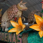 Fotografía De Primer Plano A Plena Luz Del Día Del Carro Alegórico De Cárdenas En Preparación. El Diseño Muestra Varias Figuras Monumentales De Armadillos Con Caparazones Detallados Hechos De Semillas Y Fibras Naturales, Que Parecen Emerger De Un Cañaveral.