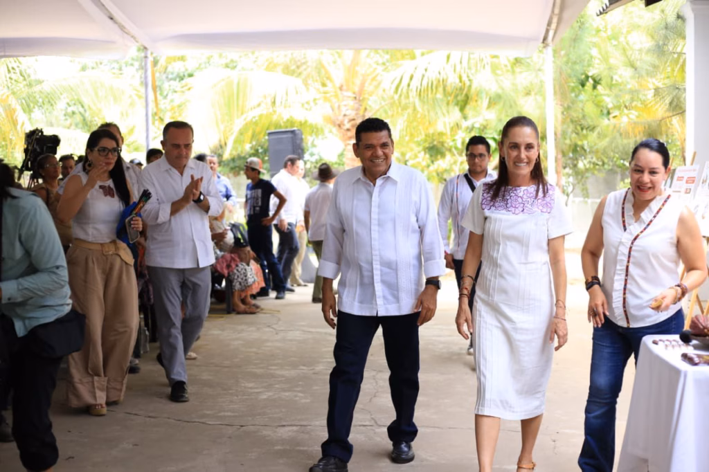 &Quot;Precio Justo Para El Cacao&Quot;: Claudia Sheinbaum Impulsa Estrategia De Exportación Y Valor Agregado En Tabasco 71 Fotografía En Plano Entero Y Toma Frontal En Exteriores Bajo Una Estructura Techada Blanca. En El Centro, La Presidenta Claudia Sheinbaum Pardo Camina Hacia El Frente Sonriendo, Vistiendo Un Vestido Blanco Con Bordados Florales Morados En El Pecho. A Su Izquierda, Un Hombre Con Guayabera Blanca De Manga Larga Y Pantalón Oscuro Camina A Su Lado Con Una Sonrisa.