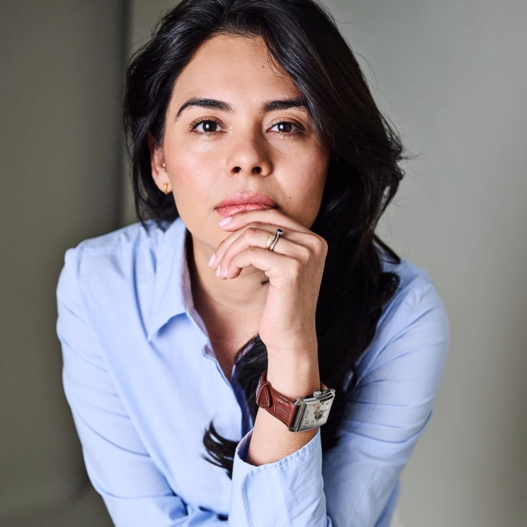 Orgullo De Tabasco En El Cine: Alejandra De La O En El Festival De Cannes 2026 71 Retrato De Plano Medio Y Encuadre Vertical De La Actriz Mexicana Alejandra De La O Posando Sonriente Al Aire Libre Durante El Festival De Cannes. La Intérprete Luce El Cabello Oscuro Recogido Hacia Atrás, Un Maquillaje Natural Y Discretos Aretes De Perla. Viste Un Elegante Blazer De Lino En Tono Beige Claro O Marfil. Sostiene Frente A Ella Un Portagafete Oficial De Color Negro Colgado Al Cuello Con La Acreditación Del Festival. El Fondo, Ligeramente Fuera De Foco, Muestra Una Terraza Soleada, Palmeras De La Riviera Francesa Y Parte De La Arquitectura Costera Bajo Un Cielo Despejado.