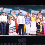Fotografía Grupal Sobre Un Escenario Iluminado Durante La Feria Tabasco. En El Centro Destaca El Gobernador Javier May Rodríguez Con Guayabera Blanca, Acompañado Por Aurora Raleigh De La Cruz (Camisa Azul Floral) Y La Flor Tabasco 2026, María José Hernández Vera, En Traje Regional Blanco. A Los Costados Se Encuentran Las Embajadoras De Emiliano Zapata Y Cunduacán, Junto A Autoridades Municipales.