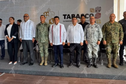 Otografía De Prensa En Plano Entero Y Ángulo Frontal Que Muestra A Diez Funcionarios Públicos Alineados De Pie Sobre Un Presídium Durante Una Conferencia De Prensa Del Gobierno De Tabasco. Al Centro Destaca El Gobernador Javier May Rodríguez Vistiendo Una Guayabera Blanca Con Bordados Verticales Rojos Y Pantalón Oscuro.