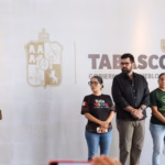 El Gobernador Javier May Rodríguez En El Podio Durante Una Conferencia De Prensa, Acompañado Por Miembros De Su Gabinete Y Equipo De Trabajo, Quienes Permanecen De Pie A Su Lado Frente A Un Muro Con El Logotipo Oficial Del Gobierno De Tabasco.