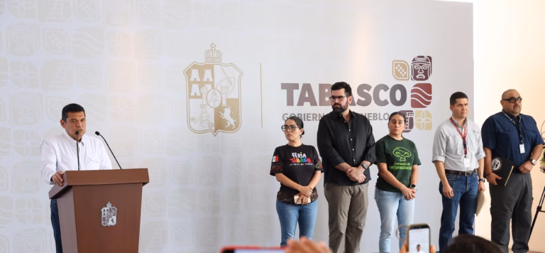 El Gobernador Javier May Rodríguez En El Podio Durante Una Conferencia De Prensa, Acompañado Por Miembros De Su Gabinete Y Equipo De Trabajo, Quienes Permanecen De Pie A Su Lado Frente A Un Muro Con El Logotipo Oficial Del Gobierno De Tabasco.