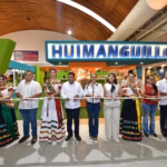 Una Fotografía Horizontal De Plano Medio Largo Captura El Corte De Listón Inaugural Del Pabellón De Huimanguillo En La Nave &Quot;Macuilis&Quot; De La Feria Tabasco 2026. Al Centro De La Imagen, El Gobernador Javier May Rodríguez, Vestido Con Guayabera Blanca Y Pantalón Oscuro, Sostiene La Cinta Junto A La Alcaldesa Mari Luz Velázquez.