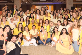 Una Fotografía Grupal A Color Captura A Un Numeroso Grupo De Emprendedores Y Organizadores De Merkadito Bazar Dentro De Un Salón Del Hotel Hyatt Regency Villahermosa. La Mayoría De Las Personas, Principalmente Mujeres, Visten Prendas En Tonos Amarillos Y Blancos, Creando Una Imagen Vibrante Y Uniforme. El Grupo Posa Sonriente Frente A La Cámara En El Marco De La 10ª Edición Del Evento; Algunos Están Sentados En El Suelo Al Frente, Mientras Otros Permanecen De Pie En Varios Niveles Hacia Atrás.
