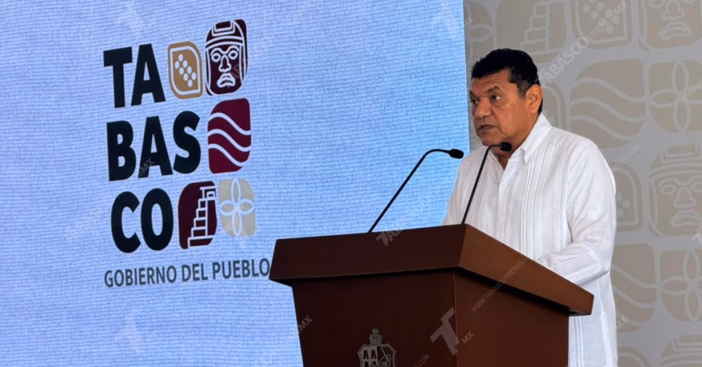 Infraestructura, Ajustes Al Gabinete Y Medidas Ante La Ola De Calor Marcan La Agenda Del Gobernador Javier May Rodríguez 71 Fotografía De Medio Cuerpo Y Toma De Perfil Tres Cuartos Orientada Hacia La Derecha. El Gobernador De Tabasco, Javier May Rodríguez, Aparece Vistiendo Una Guayabera Blanca Formal De Manga Larga, Parado Detrás De Un Podio De Madera Oscura Con El Escudo Del Estado Grabado Al Frente. El Mandatario Habla Frente A Dos Micrófonos De Cuello De Ganso. Al Fondo, A La Izquierda, Se Observa Una Pantalla Digital Iluminada En Tono Azul Claro Con La Identidad Gráfica Oficial Que Reza &Quot;Tabasco Gobierno Del Pueblo&Quot;, Acompañada De Símbolos Culturales Prehispánicos Y Regionales.