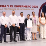 El Gobernador De Tabasco, Javier May Rodríguez, Entrega Un Reconocimiento Impreso A Una Profesional De La Enfermería En El Escenario Del Teatro Esperanza Iris. El Mandatario Viste Una Guayabera Blanca Tradicional Y Sonríe Mientras Sostiene El Galardón Junto A La Enfermera. Al Fondo Se Observa El Logotipo Oficial Del Gobierno De Tabasco Y Un Arreglo Floral.