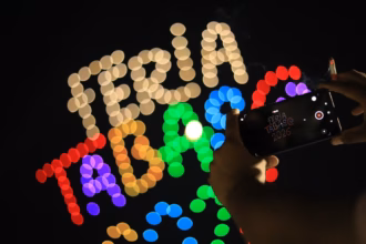 Una Persona Sostiene Un Teléfono Celular Capturando El Espectáculo De Luces En El Cielo Nocturno. Al Fondo, Drones Forman La Frase Iluminada &Quot;Feria Tabasco 2026&Quot; Con Luces Multicolores En Efecto &Quot;Bokeh&Quot;.