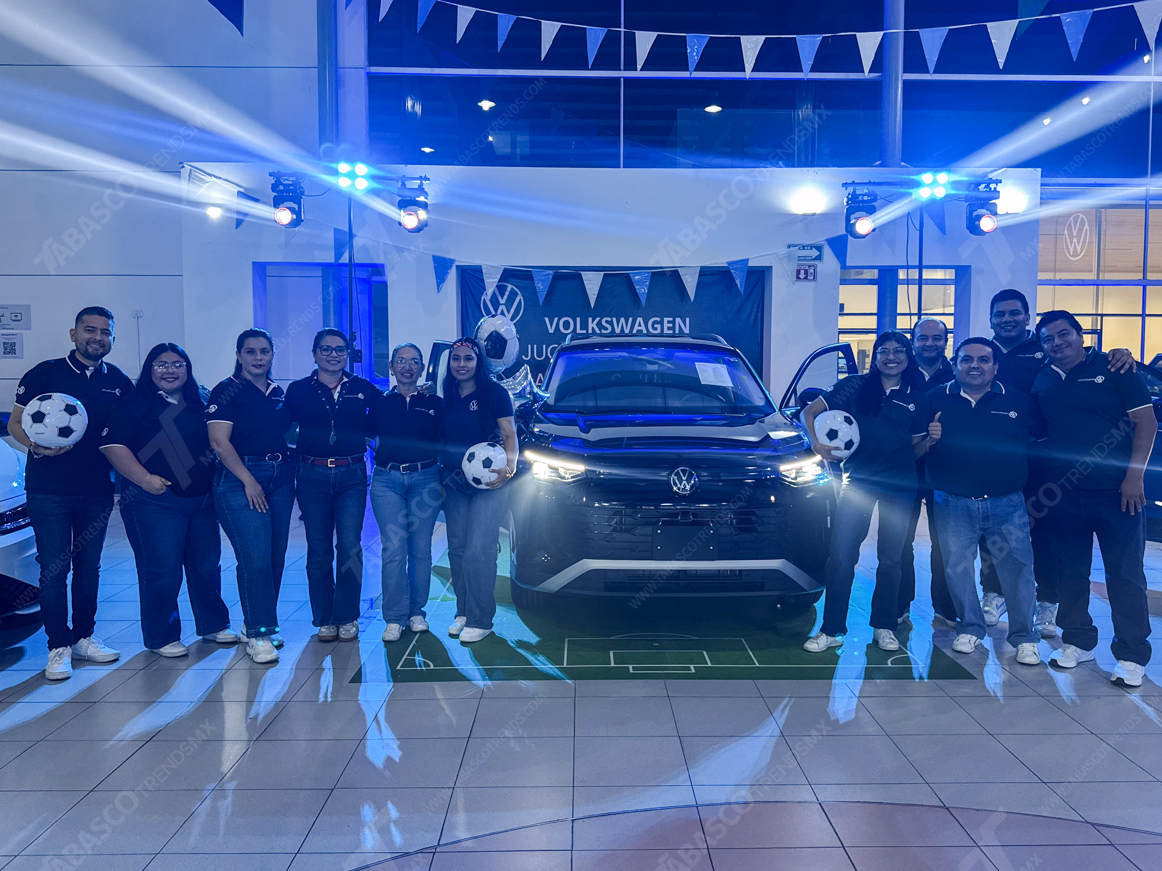 ¡Golazo De Volkswagen! Presentan Oficialmente La Edición Especial Goal 2026: Orgullo Mexicano Sobre Ruedas 70 Una Fotografía De Ángulo Medio Captura A Un Grupo Grande De Doce Empleados, De Diversas Edades Y Géneros, Posando Con Entusiasmo En Un Concesionario De Volkswagen Para El Lanzamiento De Una Edición Limitada. Visten Camisetas De Uniforme Negras Con Logos De Volkswagen Y Goal 2026.