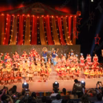 Una Fotografía De Plano General Captura El Escenario Del Teatro Esperanza Iris Durante El Espectáculo Final De La Gran Gala Anual 2023 De Relebé Studio. El Escenario Está Decorado Con El Tema &Quot;Le Cirque Du Relebé&Quot;, Con Un Telón De Circo Rojo Y Dorado, Luces Incandescentes Y Decoraciones De Estrellas.