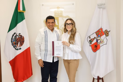 Fotografía De Plano Medio En Formato Horizontal Que Muestra Al Gobernador De Tabasco, Javier May Rodríguez, Y A La Arquitecta Alejandra Cámara Martínez Posando De Frente En Una Oficina Institucional. A La Izquierda, El Gobernador Viste Una Guayabera Blanca De Manga Larga Con Alforzas Y Bordados Azules Verticales, Combinada Con Pantalón Oscuro. A La Derecha, Alejandra Cámara