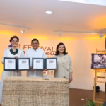 El Gobernador Javier May Rodríguez, La Directora General De Sepomex Victoria Abreu González Y La Alcaldesa Yolanda Osuna Huerta Sostienen Las Carpetas Protocolarias Del Timbre Postal Conmemorativo En El Escenario Del Festival Villahermosa 2026, Junto A Un Caballete De Madera Que Exhibe La Réplica A Gran Escala De La Estampilla De Correos De México.