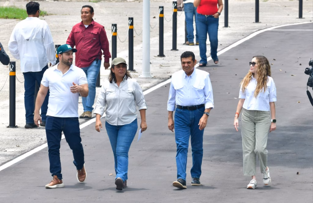 Infraestructura De Excelencia: El Nuevo Patinódromo De Olimpia Xxi Se Estrenará Con Magno Evento Regional, Anuncia Javier May 3 Fotografía En Plano Entero Que Muestra Al Gobernador De Tabasco, Javier May Rodríguez, Caminando Junto A Una Comitiva De Funcionarios Y Colaboradores Sobre El Pavimento Asfáltico De Una Vialidad En El Deportivo Olimpia Xxi. El Gobernador, Ubicado Hacia El Centro-Derecha, Viste Una Camisa Blanca De Manga Larga Arremangada, Pantalones De Mezclilla Azules Y Zapatos Oscuros.
