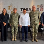 Fotografía De Plano Entero Y Horizontal Que Muestra Al Gobernador De Tabasco, Javier May Rodríguez, Al Centro De Una Línea De Diez Funcionarios Públicos Y Mandos Militares Sobre Un Presídium. El Gobernador Viste Una Guayabera Blanca Y Pantalón Oscuro.