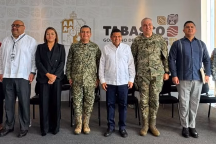 Fotografía De Plano Entero Y Horizontal Que Muestra Al Gobernador De Tabasco, Javier May Rodríguez, Al Centro De Una Línea De Diez Funcionarios Públicos Y Mandos Militares Sobre Un Presídium. El Gobernador Viste Una Guayabera Blanca Y Pantalón Oscuro.