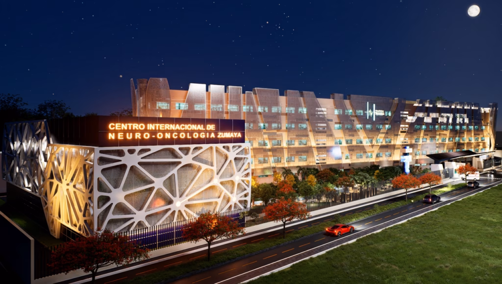 Hospital Zumaya En Villahermosa: El Nuevo Gigante Médico Del Sureste 72 Una Representación Arquitectónica Digital De Alta Calidad (Render) De La Fachada Exterior Del Hospital Zumaya En Villahermosa, Tabasco, Durante La Noche Bajo Un Cielo Estrellado Y Luna Llena. Se Aprecian Dos Estructuras Principales Conectadas: A La Izquierda, Un Bloque Más Bajo Con Una Llamativa Celosía Geométrica Orgánica De Color Blanco Y Un Letrero Iluminado Que Dice 'Centro Internacional De Neuro-Oncología Zumaya'. A La Derecha, Un Edificio De Varios Pisos Con Una Fachada De Paneles Modernos Y Ventanas Iluminadas, Con El Logotipo Y Nombre 'Hospital Zumaya' En La Parte Superior. Al Frente, Una Calle Pavimentada Con Un Auto Deportivo Rojo Y Árboles De Flamboyán En Flor Que Delimitan El Perímetro.