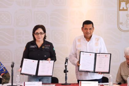 Fotografía De Prensa En Interiores Que Muestra A La Coordinadora Nacional De Protección Civil, Laura Velázquez Alzúa, Y Al Gobernador De Tabasco, Javier May Rodríguez, De Pie Detrás De Una Mesa Con Mantel Rojo. Ambos Sostienen Carpetas Abiertas Mostrando Documentos Oficiales Firmados, En El Evento Capturado En &Quot;Javier May Coordina Plan De Emergencia Por Temporada De Lluvias En Tabasco