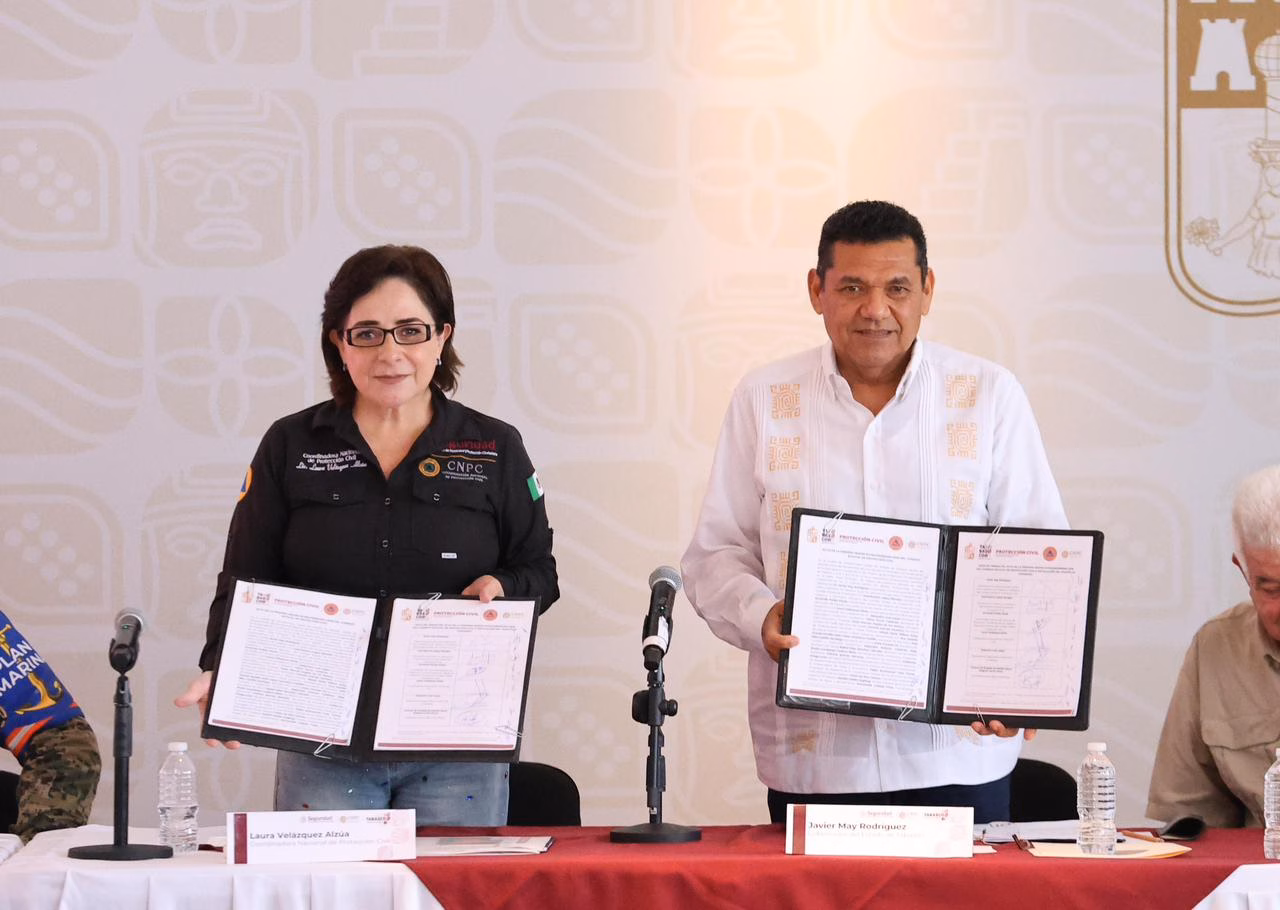 Javier May Coordina Plan De Emergencia Por Temporada De Lluvias En Tabasco 70 Fotografía De Prensa En Interiores Que Muestra A La Coordinadora Nacional De Protección Civil, Laura Velázquez Alzúa, Y Al Gobernador De Tabasco, Javier May Rodríguez, De Pie Detrás De Una Mesa Con Mantel Rojo. Ambos Sostienen Carpetas Abiertas Mostrando Documentos Oficiales Firmados, En El Evento Capturado En &Amp;Quot;Javier May Coordina Plan De Emergencia Por Temporada De Lluvias En Tabasco