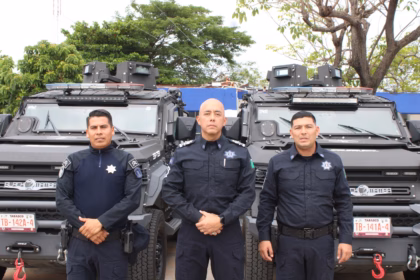 Tres Elementos Masculinos De La Secretaría De Seguridad Y Protección Ciudadana De Tabasco Posan De Pie Y De Frente En Plano Medio, Vistiendo Uniformes Policiales Oficiales De Color Azul Marino Con Insignias Y Placas En El Pecho. Detrás De Ellos Se Encuentran Estacionadas Dos Patrullas Blindadas Tácticas De Color Negro Tipo &Quot;Black Mamba&Quot; Con Luces De Torreta En El Techo Y Placas De Circulación Del Estado De Tabasco Visibles Al Frente. De Fondo Se Aprecian Árboles Verdes Bajo Un Cielo Claro.