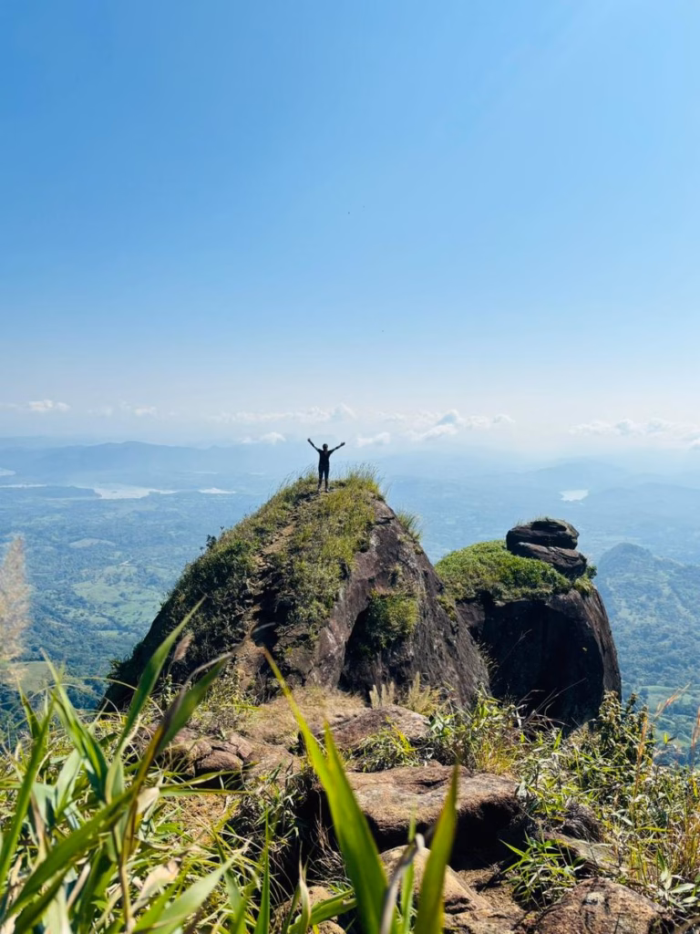 Una Persona De Pie Con Los Brazos Abiertos En Señal De Triunfo Sobre El Pico Rocoso Del Cerro La Pava. A Su Alrededor Se Observa Un Paisaje Panorámico De Montañas, Valles Verdes Y Un Cielo Despejado De Azul Intenso.
