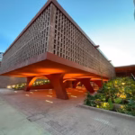 Fachada Moderna Y Arquitectónica Del Museo Regional &Quot;La Cacaotera&Quot; En Villahermosa, Elaborada Con Ladrillo En Celosía De Tono Terracota, Pilares Curvos E Iluminación Cálida Al Atardecer.