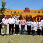 Un Grupo De Ocho Directivos Del Hospital Zumaya Y Autoridades Académicas De La Universidad Autónoma De Guadalajara (Uag) Campus Tabasco Posan Para Una Fotografía Frente A Las Letras Rojas Monumentales De La Universidad. El Grupo Está Compuesto Por Cuatro Hombres De Civil (Incluyendo Al Ceo Alejandro Yusseff Nieves), Una Mujer De Civil (Dra. Jessica Cristell García Cruz) Y Tres Médicos Con Bata Blanca (Incluyendo A La Dra. María Elena De La O De La O). Todos Miran A La Cámara Sonrientes En Un Día Soleado.