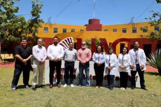Un Grupo De Ocho Directivos Del Hospital Zumaya Y Autoridades Académicas De La Universidad Autónoma De Guadalajara (Uag) Campus Tabasco Posan Para Una Fotografía Frente A Las Letras Rojas Monumentales De La Universidad. El Grupo Está Compuesto Por Cuatro Hombres De Civil (Incluyendo Al Ceo Alejandro Yusseff Nieves), Una Mujer De Civil (Dra. Jessica Cristell García Cruz) Y Tres Médicos Con Bata Blanca (Incluyendo A La Dra. María Elena De La O De La O). Todos Miran A La Cámara Sonrientes En Un Día Soleado.