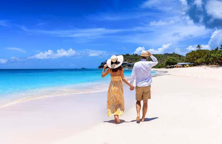 Una Pareja Caminando De La Mano Por La Orilla De Una Playa Paradisíaca De Arena Blanca Y Mar Turquesa, Representando Las 3 Playas Cerca De Tabasco Que Te Sorprenderán Este Verano.