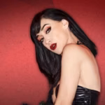 Retrato Promocional De La Cantante Y Actriz Mexicana Susana Zabaleta Gratis En Villahermosa, Luciendo Cabello Negro Corto, Labial Rojo Y Vestuario Glamuroso Sobre Un Fondo Rojo.
