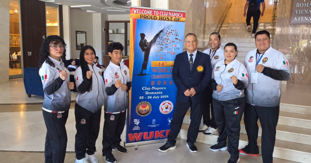 Delegación Mexicana De Karatecas, Entre Ellos Los Tabasqueños Víctor Montejo Y Anayeli Rodríguez, Posando En El Vestíbulo Del Evento Junto A Un Banner Promocional Del 14Th Wukf World Championships En Cluj-Napoca, Rumania.