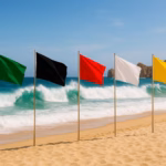 Cinco Mástiles Alineados En La Arena Con Las Banderas De Seguridad Verde, Negra, Roja, Blanca Y Amarilla Frente Al Mar Para Indicar El Sistema De Banderas En La Playa.
