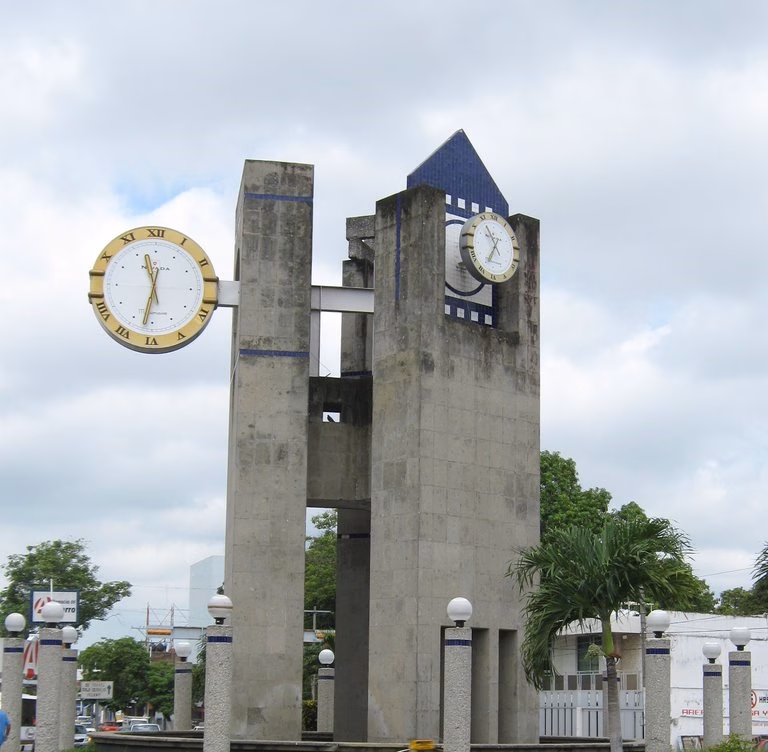 Monumento Del Reloj De Las Tres Caras En Villahermosa, Tabasco, Mostrando Su Torre Brutalista De Concreto Expuesto Con Carátulas Circulares Y Azulejos Azules.