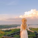 Una Mujer De Espaldas Con Vestido Blanco Y Sombrero De Paja Contempla Un Vasto Paisaje De Selva Verde Y El Río Usumacinta Desde Un Mirador Al Atardecer.