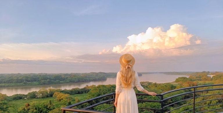 Una Mujer De Espaldas Con Vestido Blanco Y Sombrero De Paja Contempla Un Vasto Paisaje De Selva Verde Y El Río Usumacinta Desde Un Mirador Al Atardecer.