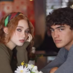 Daniela Martínez Y Tristán Maze, Protagonistas De La Serie De Netflix 'Proyecto Final', Miran Fijamente A La Cámara Sentados En Una Mesa De Restaurante Con Un Florero En Dominion Polanco.