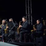 Músicos De La Sección De Saxofones De La Banda Sinfónica Del Gobierno Del Estado De Tabasco Interpretando En Un Escenario Nocturno Al Aire Libre.