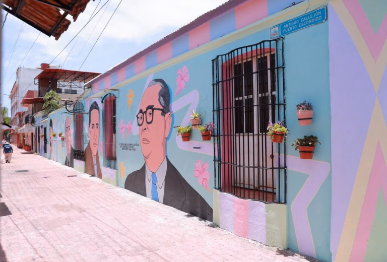 Vista De Ángulo Bajo De Un Vibrante Mural Callejero Que Cubre La Pared De Un Edificio. El Mural Representa Retratos Estilizados De Personajes Históricos Con Gafas, Intercalados Con Motivos Florales Abstractos Y Líneas Geométricas. La Pared Tiene Macetas Colgantes Y Una Ventana Con Rejas. El Suelo Es De Adoquines De Terracota.
